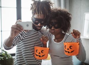 Young couple celebrating Halloween. They wear costumes, smiling, taking selfie and enjoy in holiday, diy halloween costume