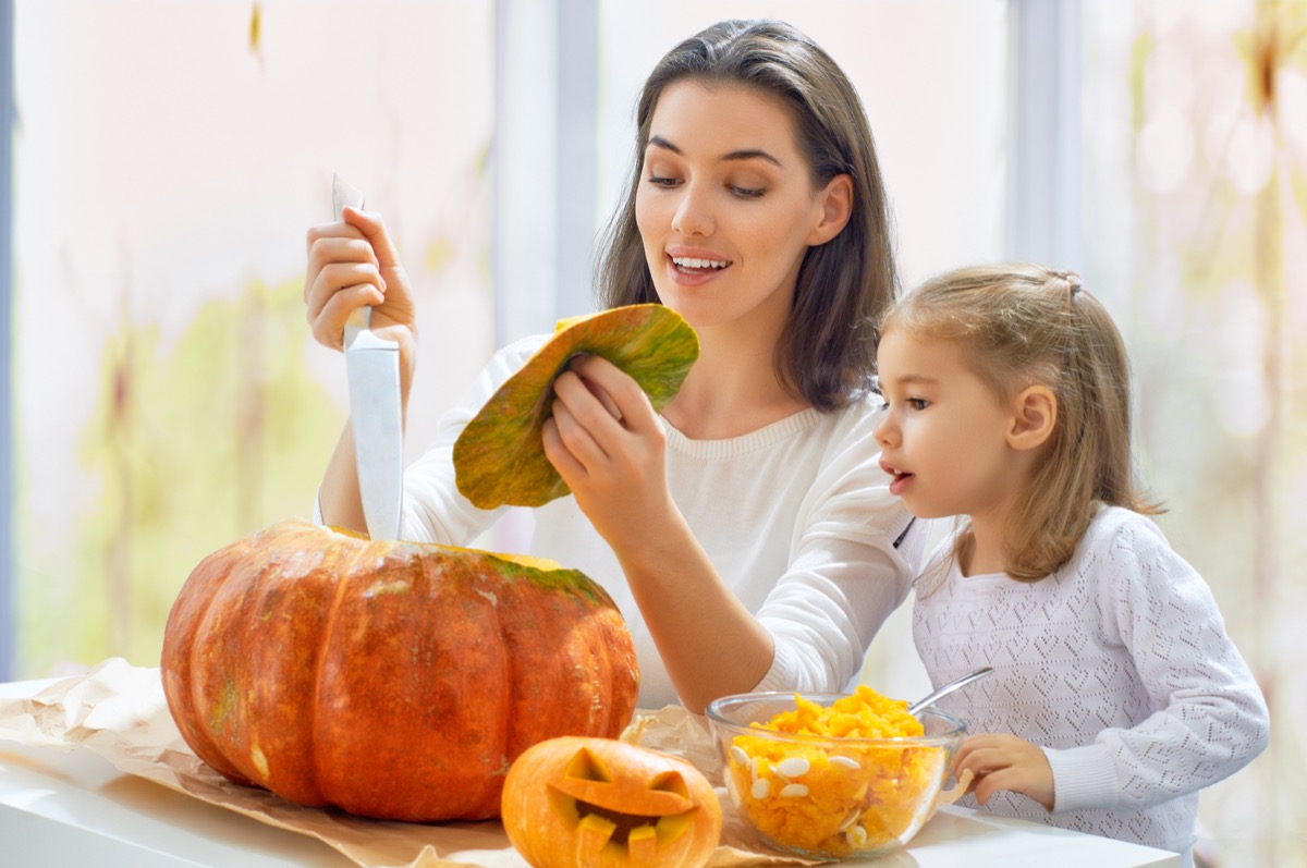 child and mother carving a pumpkin