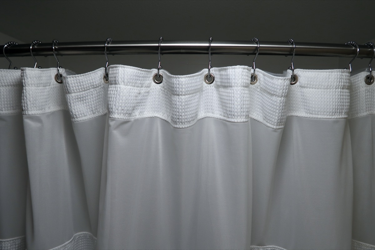 white shower curtain on curved rod