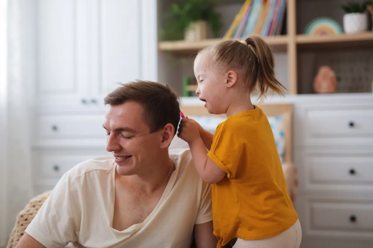 Young daughter brushing her dad's hair being a step-parent