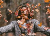 Woman throwing crunchy fall leaves in the air fall weather health
