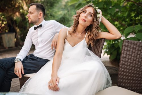 white woman in wedding dress looking sad near white husband outdoors