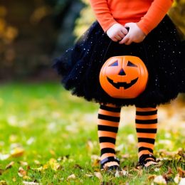 little girl holding trick or treating pumpkin on halloween