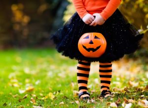 little girl holding trick or treating pumpkin on halloween