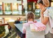 little girl looking at a mall directory with her mother