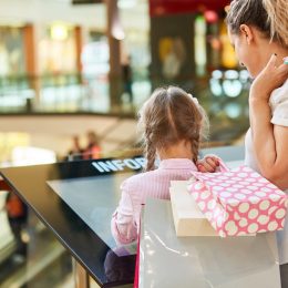 little girl looking at a mall directory with her mother