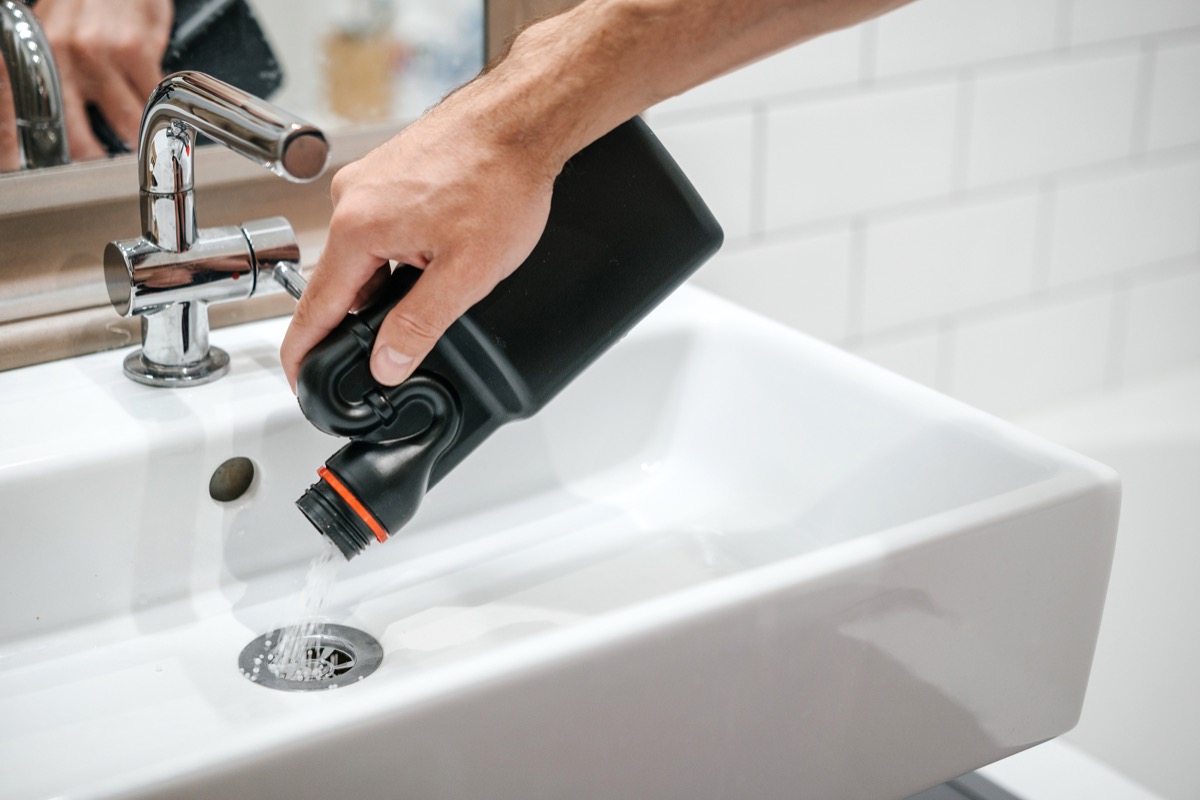 man pouring chemical drain cleaner down a sink