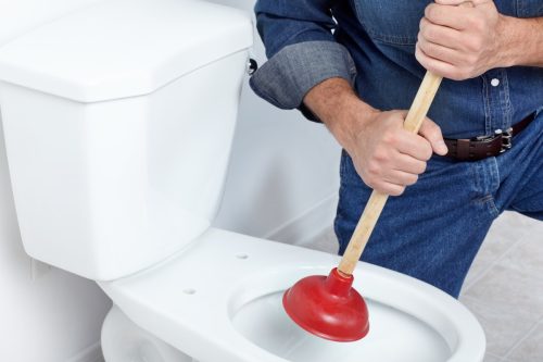 man using plunger on toilet, property damage