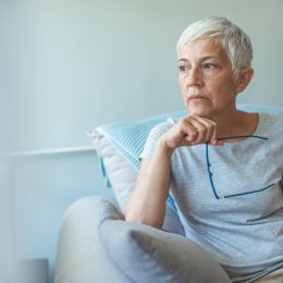 older woman sitting on the couch looking worried
