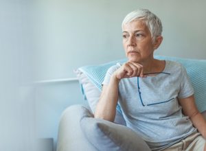 older woman sitting on the couch looking worried
