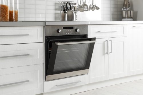 open stainless steel oven in a white modern kitchen, fire prevention tips