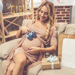 pregnant woman holding baby booties over stomach, pregnant gifts