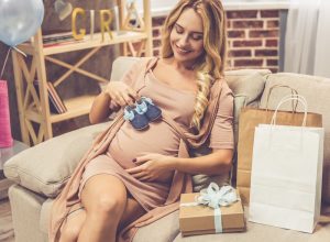 pregnant woman holding baby booties over stomach, pregnant gifts
