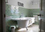 bathroom with freestanding tub and green subway tile, bathroom accessories