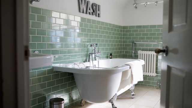 bathroom with freestanding tub and green subway tile, bathroom accessories