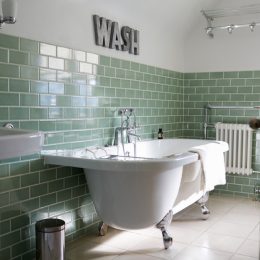 bathroom with freestanding tub and green subway tile, bathroom accessories
