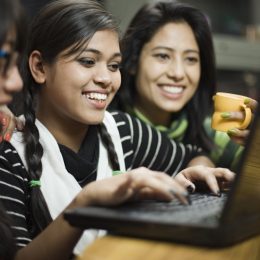 Indoor image of a group of late teen girls from different ethnicities using laptop together