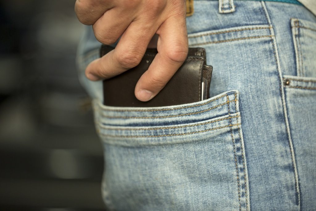 Man putting his wallet in his back pocket damaging body