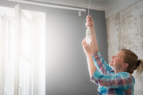 A woman changes the light bulb in the pendant lamp