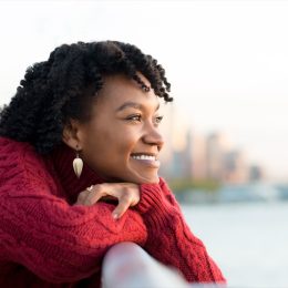 woman thinking and smiling on the side of a bridge