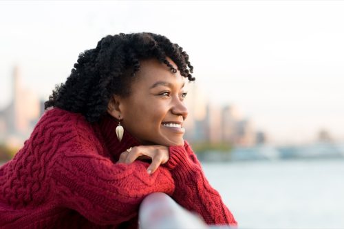 woman thinking and smiling on the side of a bridge