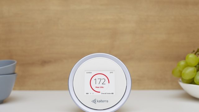 white circular air quality monitor device in front of brown wall