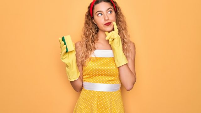 Woman in yellow dress with sponge and cleaning gloves