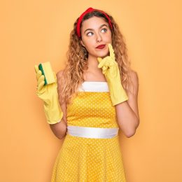 Woman in yellow dress with sponge and cleaning gloves