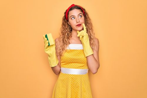 Femeie care poartă rochie galbenă cu burete și mănuși de curățat