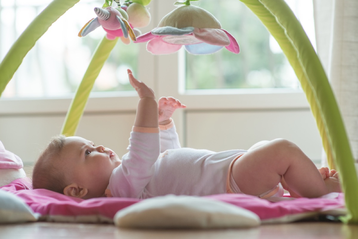 white baby lying on back on play mat
