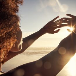Rearview shot of a young woman blocking the sunlight with her hands at the beach