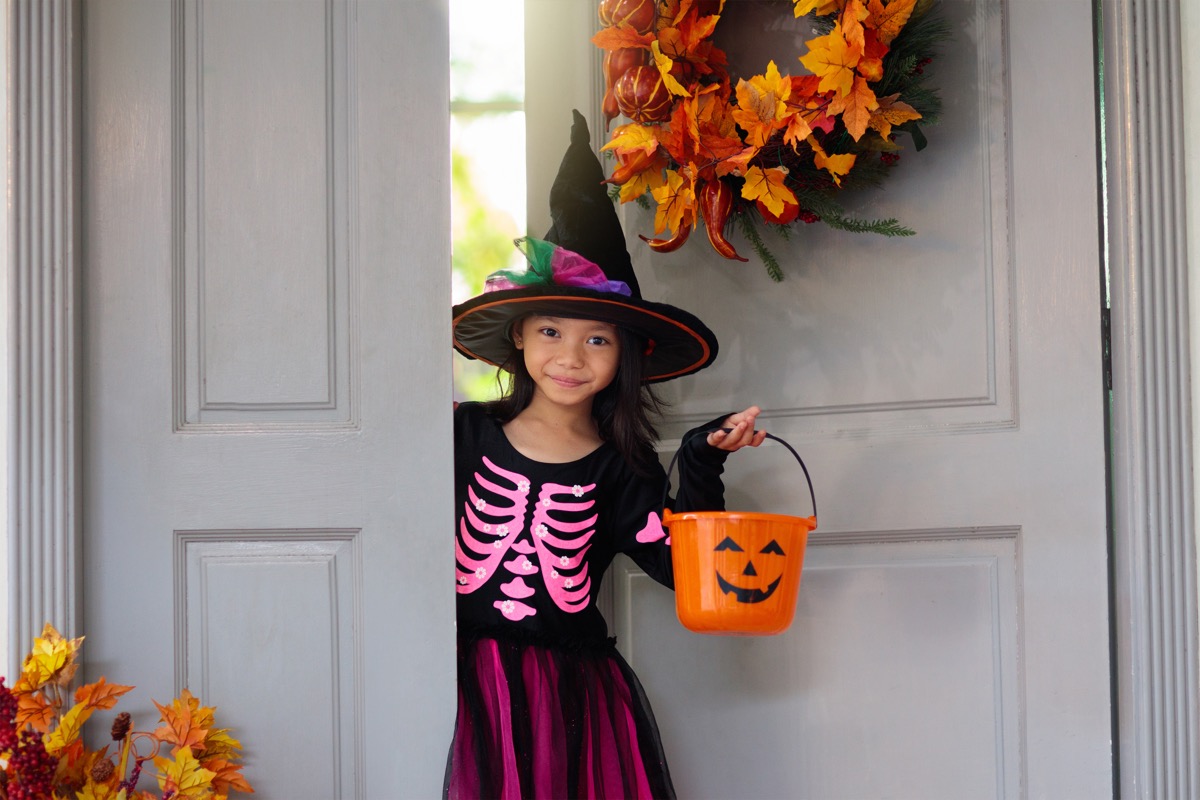 little girl in witch hat going trick or treating on halloween