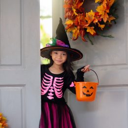 little girl in witch hat going trick or treating on halloween