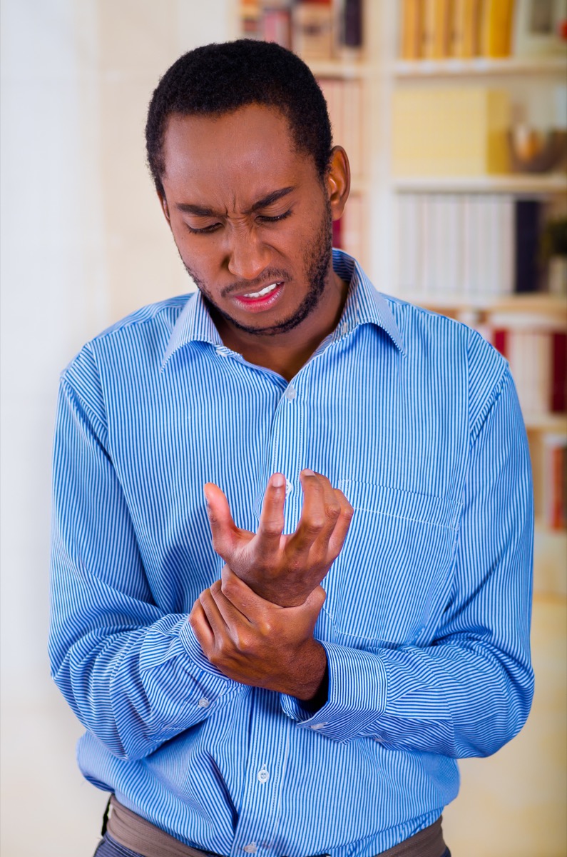 Black man holding his wrist in pain because of carpal tunnel syndrome
