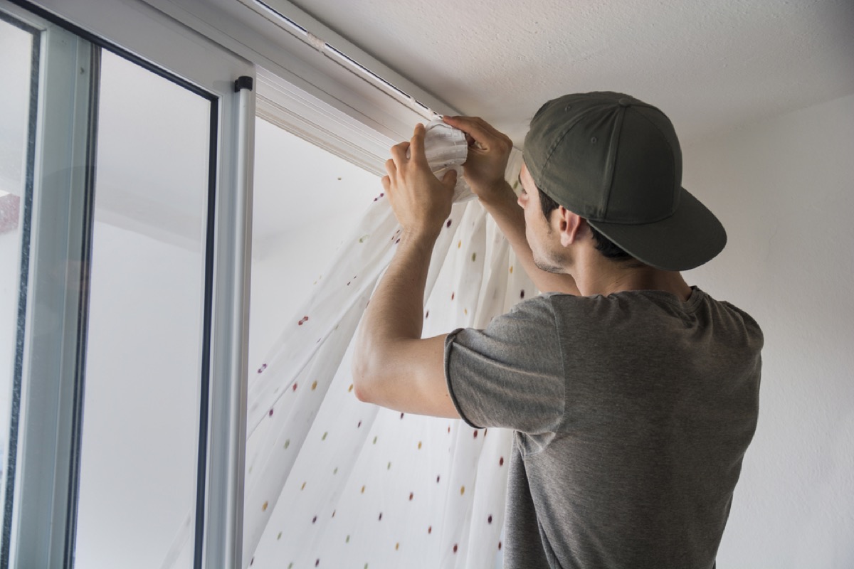 man installing curtains