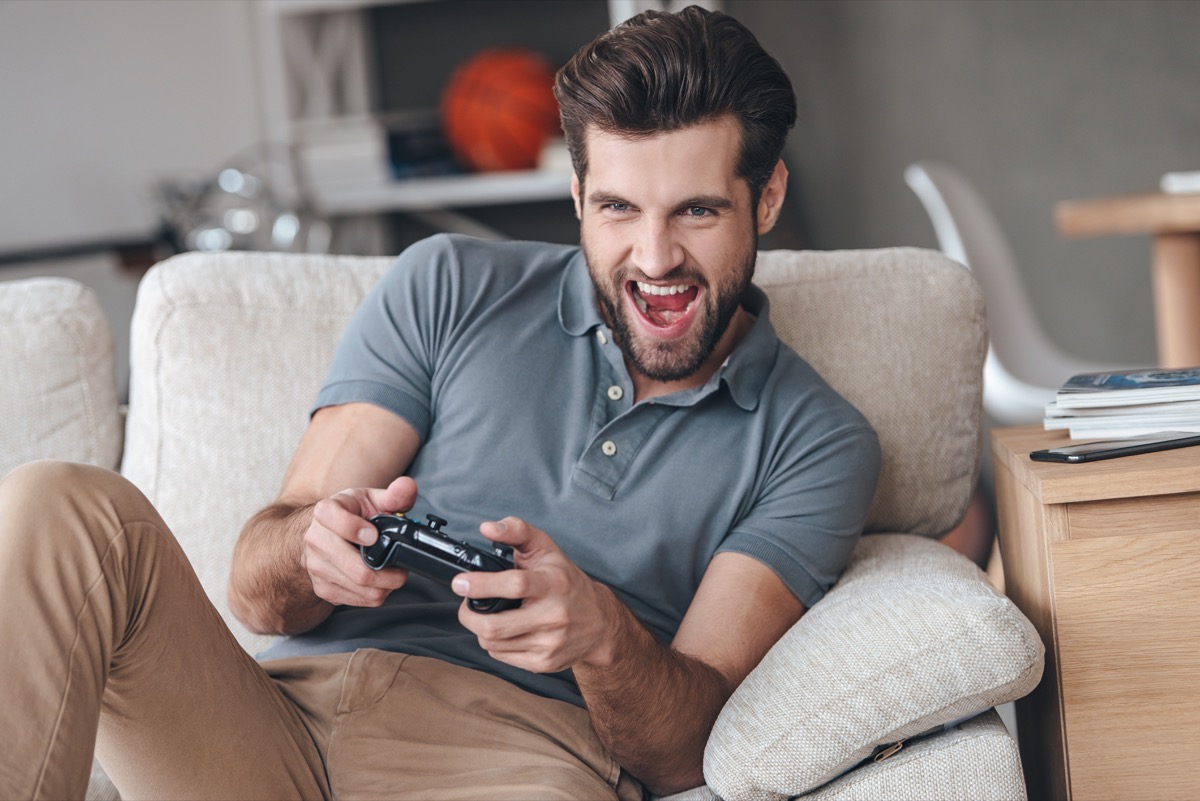 man playing video games on couch