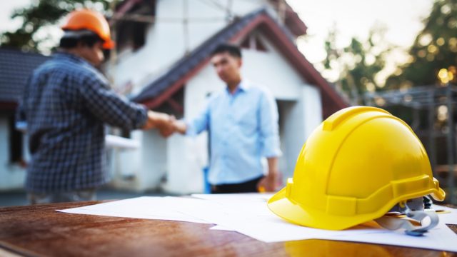 man shaking hands with a contractor outside his house