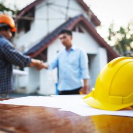 man shaking hands with a contractor outside his house