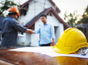 man shaking hands with a contractor outside his house