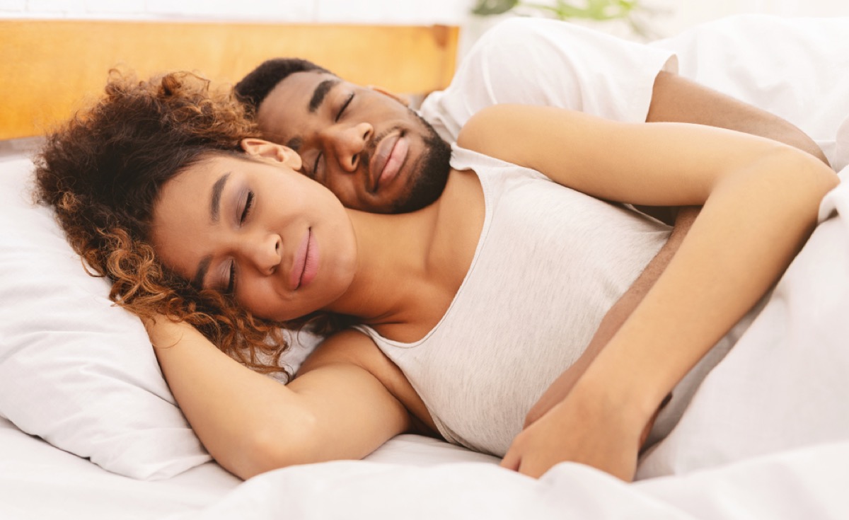 black man and woman sleeping in bed with white sheets, better sleep essentials