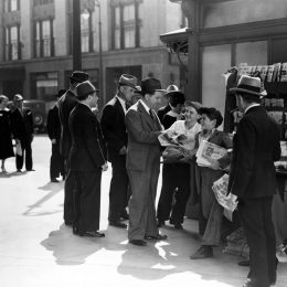 men buying newspapers from newsboys shouting extra extra in the middle of the 20th century