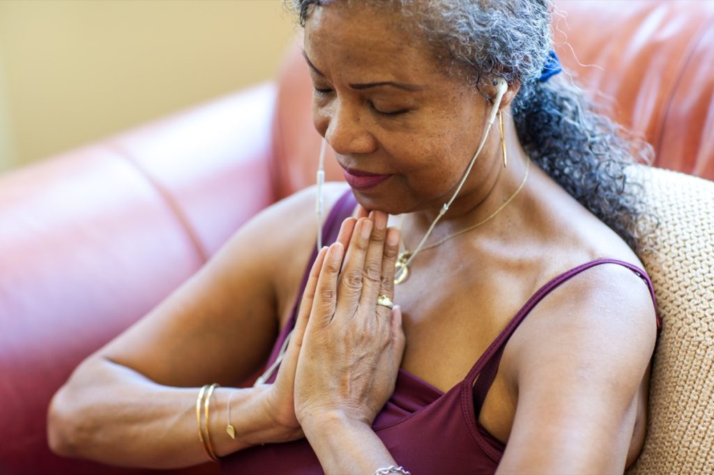 Older woman listening to music and meditating on the couch