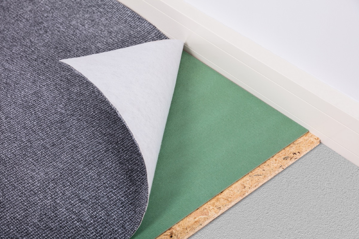 gray rug peeling back from green rug pad