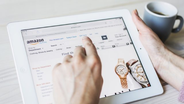 woman's hand clicks on tablet screen while shopping on amazon for watches