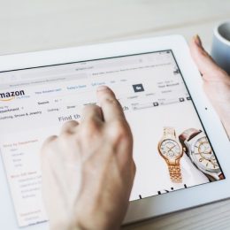 woman's hand clicks on tablet screen while shopping on amazon for watches