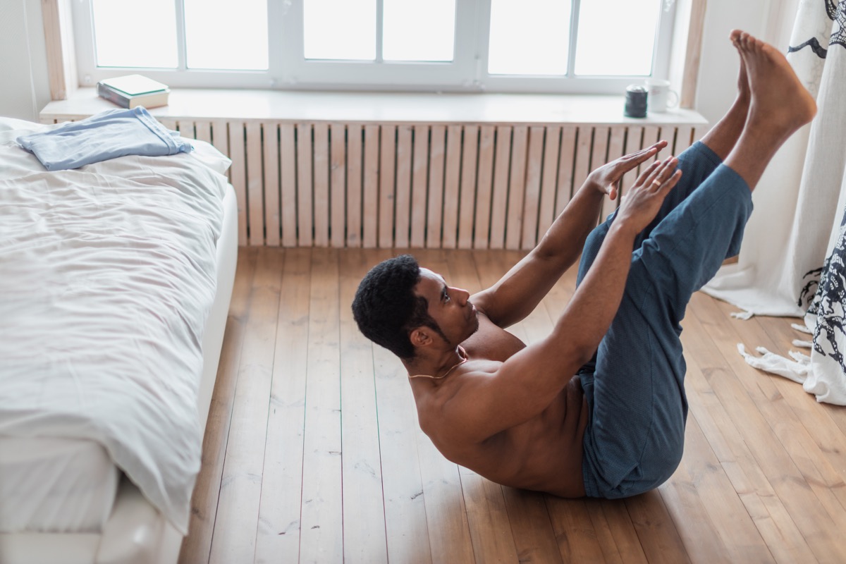 Man doing sit-ups at home on the floor of his bedroom