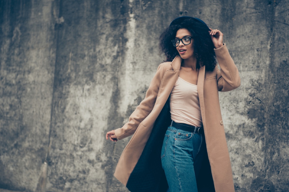 stylish black woman standing outdoors in camel coat