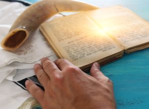 man reading torah with tallit and shofar behind it