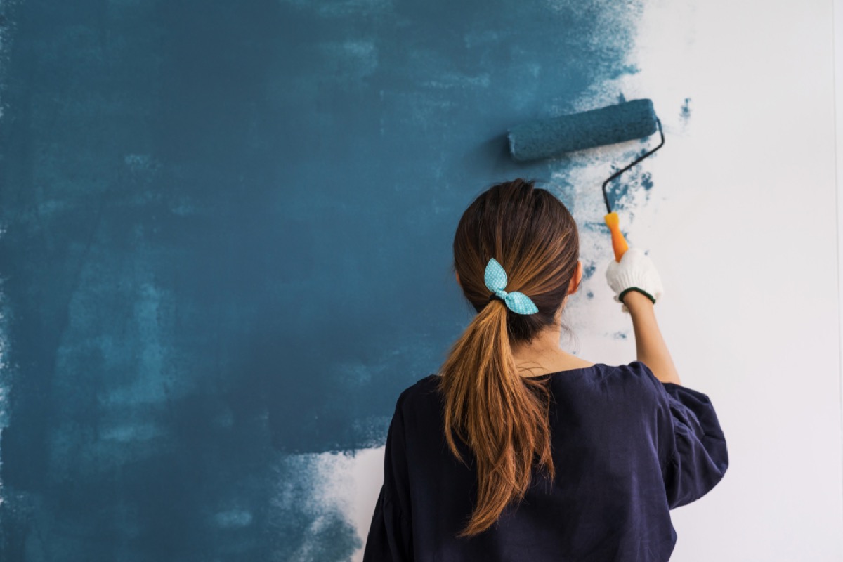 woman painting walls blue