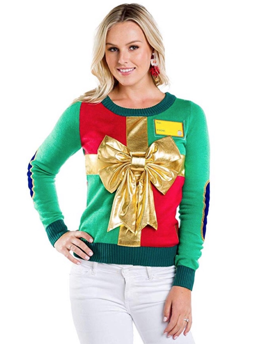 woman wearing christmas sweater that looks like a wrapped gift with a gold bow